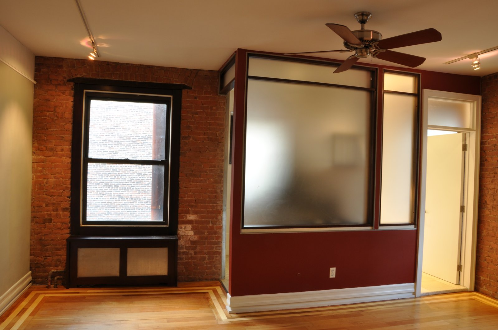 Main room — corner view with exposed brick window wall